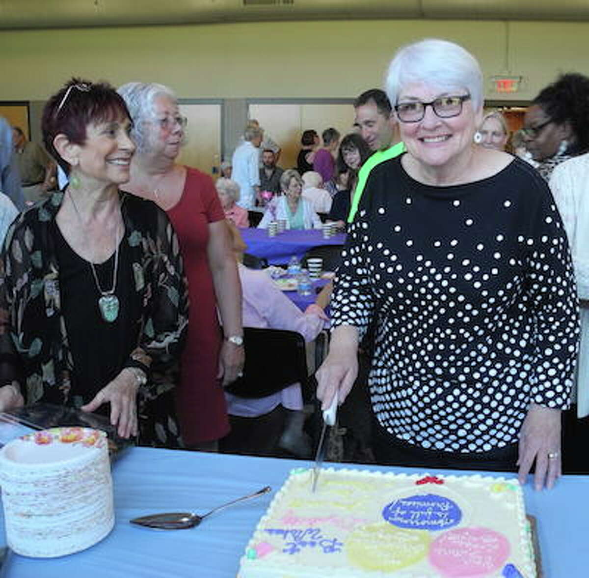 Liz Doty, who stepped down as Wilton's senior activities coordinator, cuts a cake at her farewell party as social worker Lauren Hughes looks on. - Jeannette Ross photo