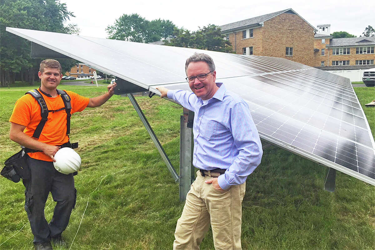 Corey Koenig, co-owner of KMK Solar Structures, joins Mark Robbins, founder and president of MHR Development, at the ground-mounted solar array at the School Sisters of Notre Dame campus on Belden Hill road. KMK Solar Structures installed the solar panels. — Contributed photo