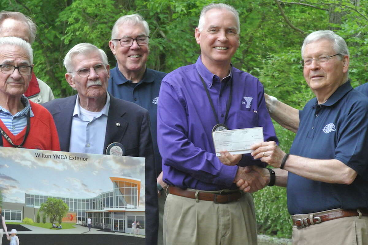 Kiwanians, from left, Jim Turnbull, Paul Young and Marty Clancy look on as Bob McDowell, executive director of the YMCA, accepts a check from John Kalamarides on behalf of the Wilton Kiwanis Club. — Tony Spinelli photo
