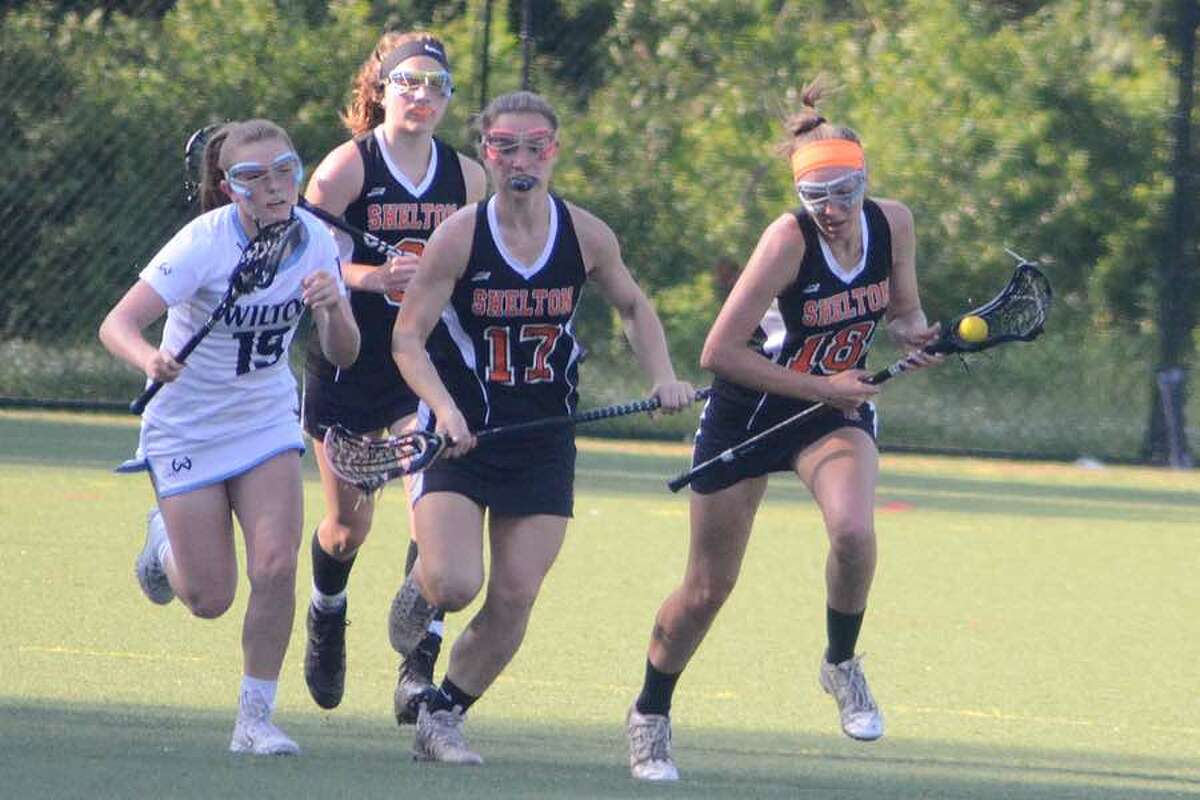 Shelton's Danielle Kreitler takes the ball up the field, while Wilton's Cassidy Costello (left) gives chase, during Tuesday's Class L girls lacrosse game at Wilton.