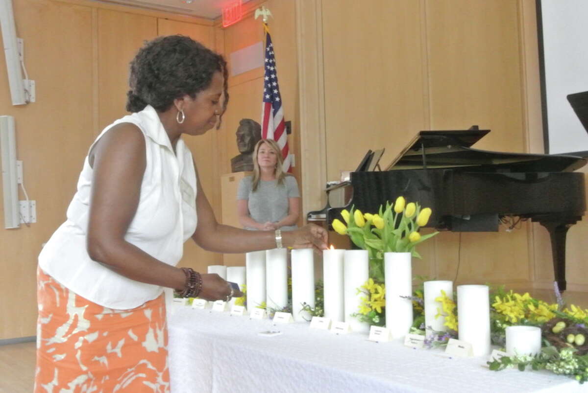 Adrienne Reedy lights the unity candle at Thursday’s service commemorating National Prayer Day. Joan Wallace, in the background, sang We Are One during the service. — Jeannette Ross photo