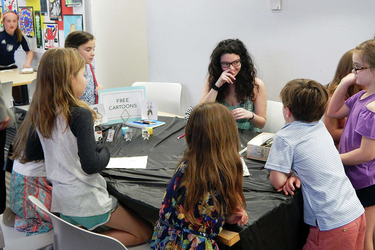 Wilton student creates free cartoons at the FAPA Exhibit opening reception.