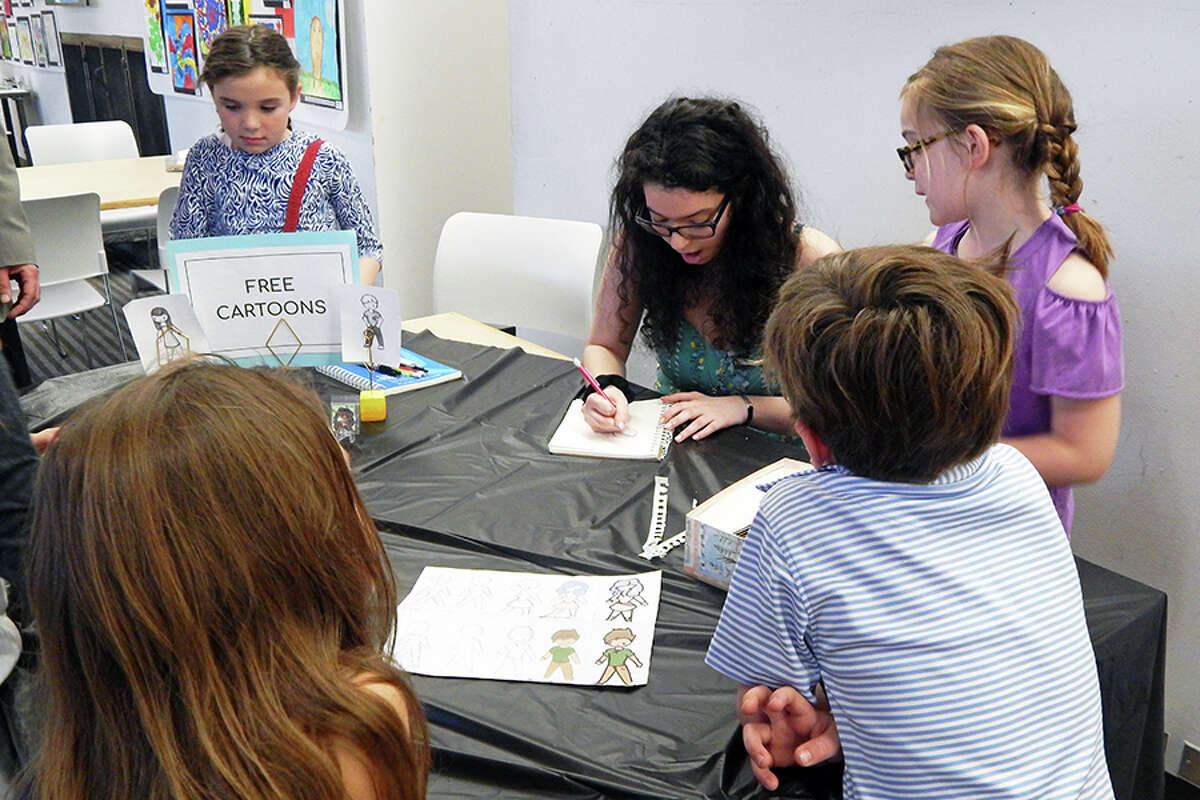 Wilton student creates free cartoons at the FAPA Exhibit opening reception.