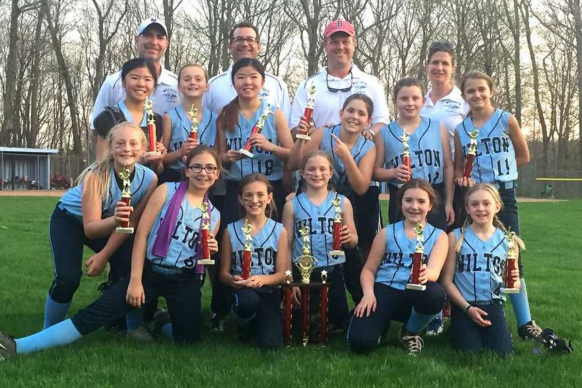 The Wilton Blue 10U softball team after winning the Sunrise Cottage Tournament in Ridgefield on Wednesday. From the left, front row: Ava Gaudio, Kaitlin Feldman, Sophia Viggiano, Emma van Heyst, Grace Couch and Allison Rayment; middle row: Ellie Qudeen, Sarah Morris, Grace Qudeen, Annie McMahon, Kayleigh Whitters and Sofia Samai; and back row: coaches Aaron Feldman, Tom Viggiano, Matt McMahon and Amanda Samai. — Beth Anne McMahon photo