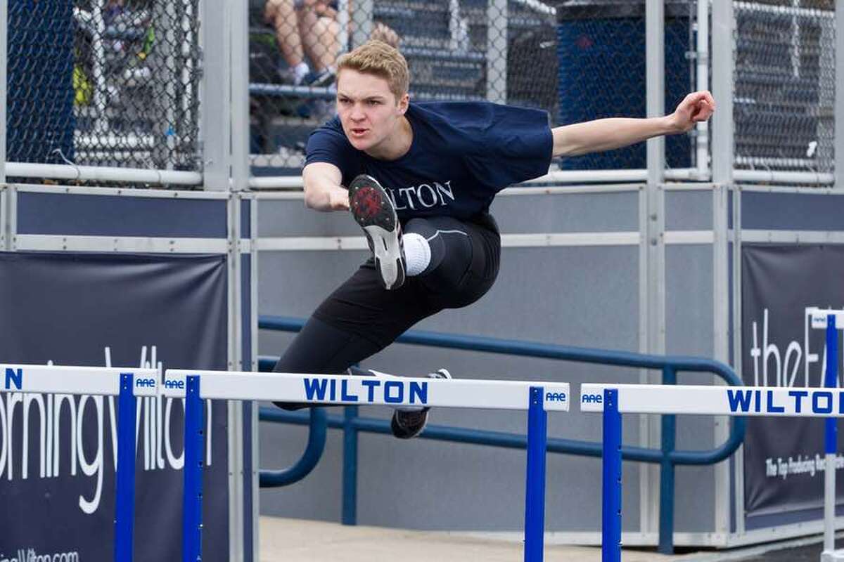 Charlie Golbourn clears the barrier in the 110-meter hurdles during Wilton track and field action. - GretchenMcMahonPhotography.com
