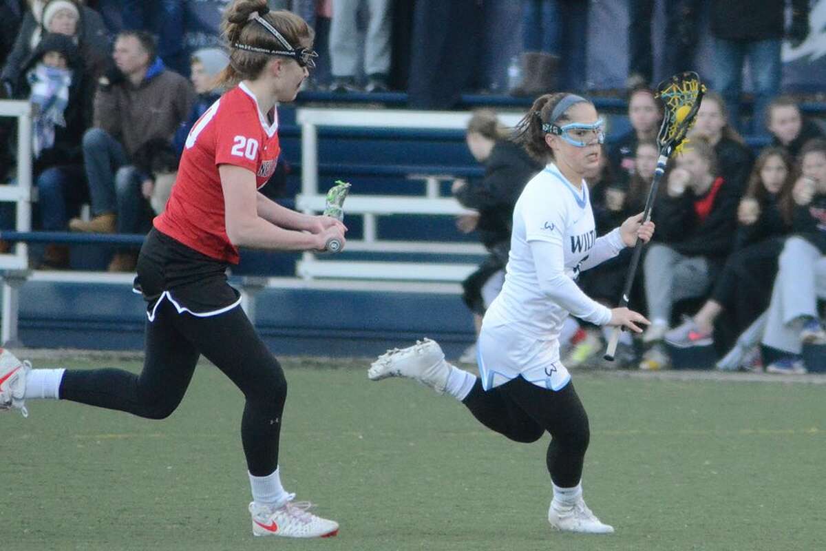 Sophia Sudano tries to elude New Canaan's Leigh Charlton during the Wilton girls lacrosse team's 6-4 loss to the Rams on Thursday in Wilton. — J.B. Cozens photo
