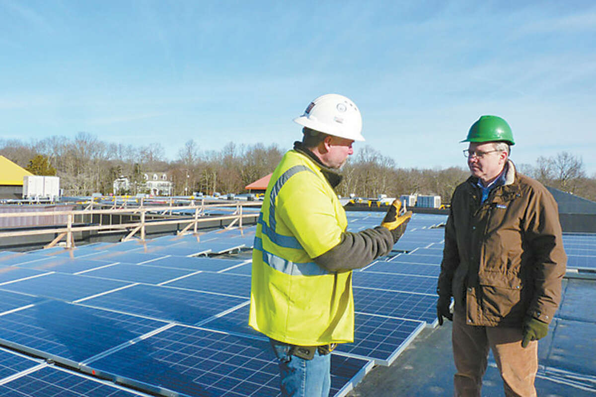 Peter Tevendale of Windward Solar, left, and Mark Robbins, founder and president of MHR Development, discuss the solar panel array on the roof of Miller-Driscoll School. — Contributed photo