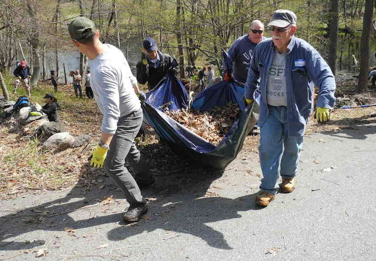 From left, Hong Som, Anthony Tran, Joe Cheh, and George Hine haul a tarp full of leaves, invasive plants, and other debris from the area around the pond at Slaughter Fields.