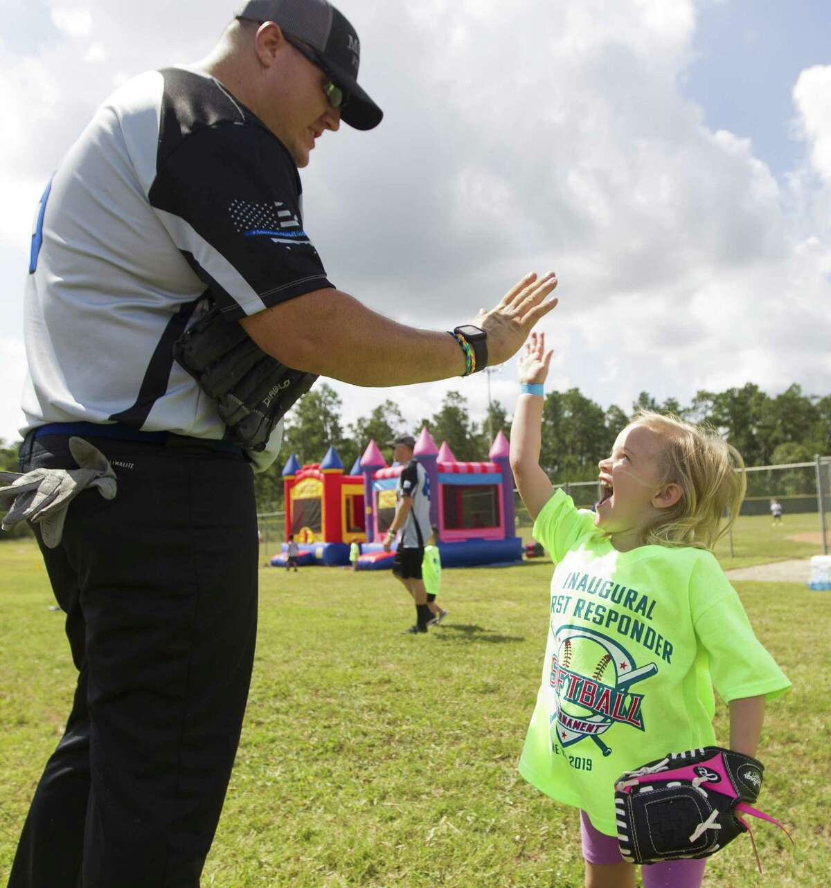 Montgomery County Sheriff’s Office Deputy Dylan Jobe gives a high-five to his daugher Edriana after catching a ball before the kids for cops game, as part of the inaugural Americans Stand United First Responder Softball Tournament at Carl Barton, Jr. Park, Saturday, June 15, 2019, in Conroe. Each child was pair with a firefighter or police officer as a coach for the game. The inaugural tournament brought together community members with 150 first responders from Montgomery and Harris County.