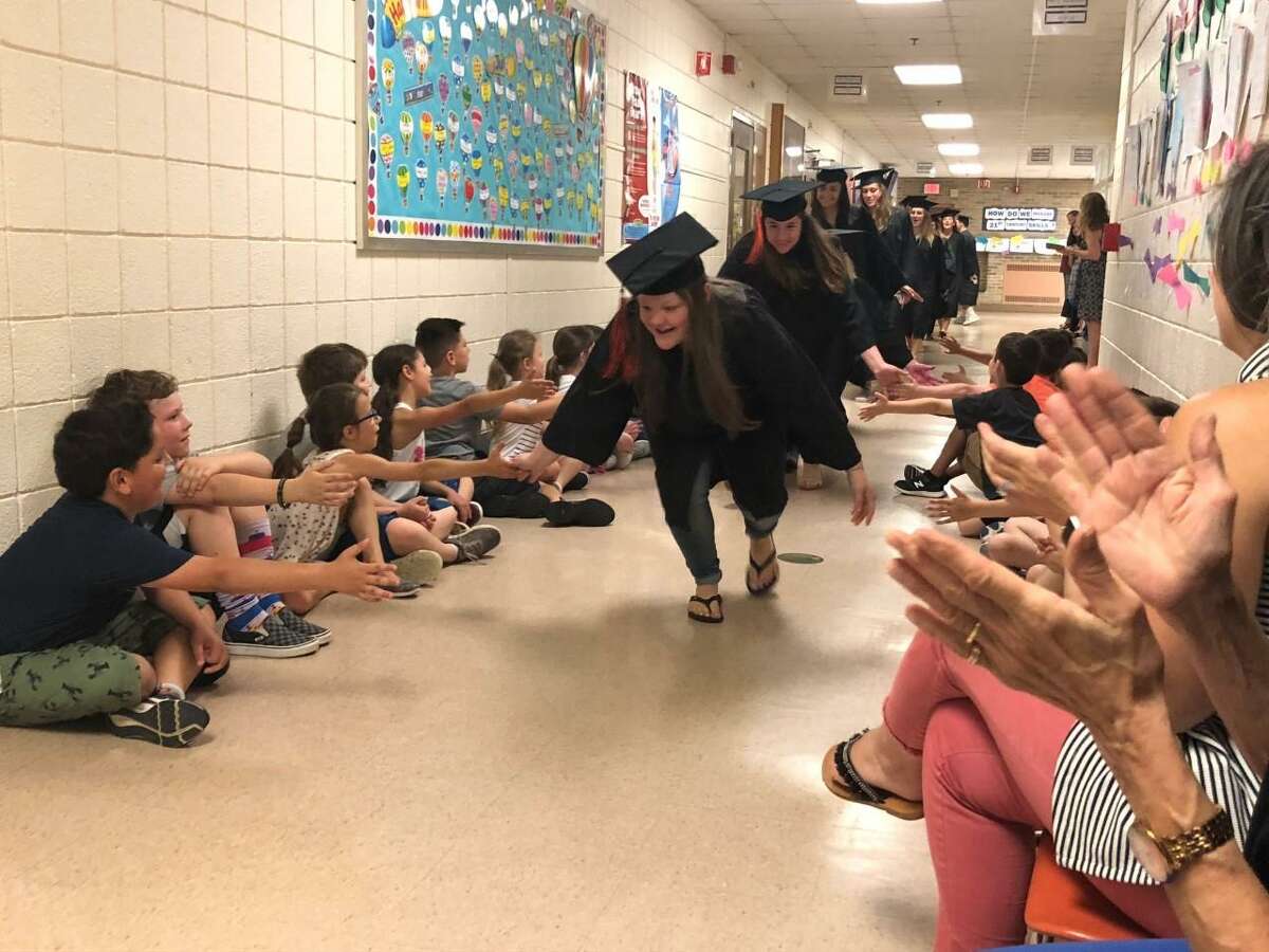 It was high fives all around as graduating seniors visited their original elementary schools Thursday, June 6. Above, some seniors got cheered on my youngsters.