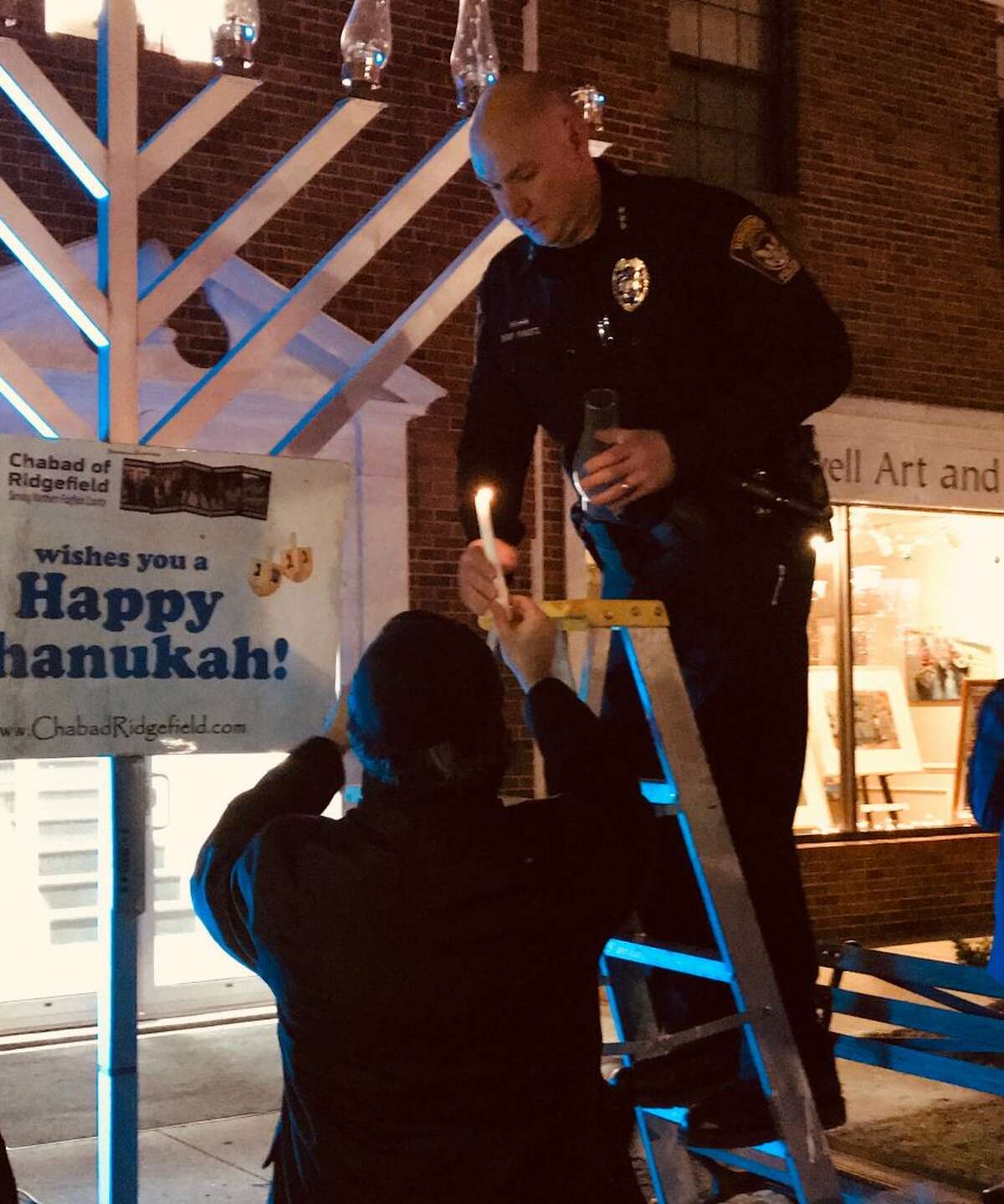 Police Chief Jeff Kreitz lights a candle during the Hanukah walk on Main Street on Dec. 7.