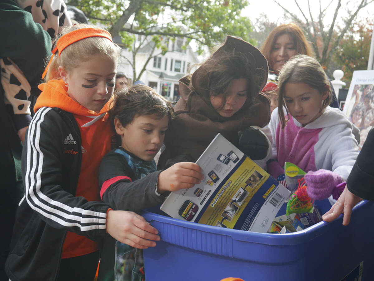 Young trick-or-treaters reach inside the giveaway bin outside the Toy Chest during last fall's Halloween Walk. - Steve Coulter photo