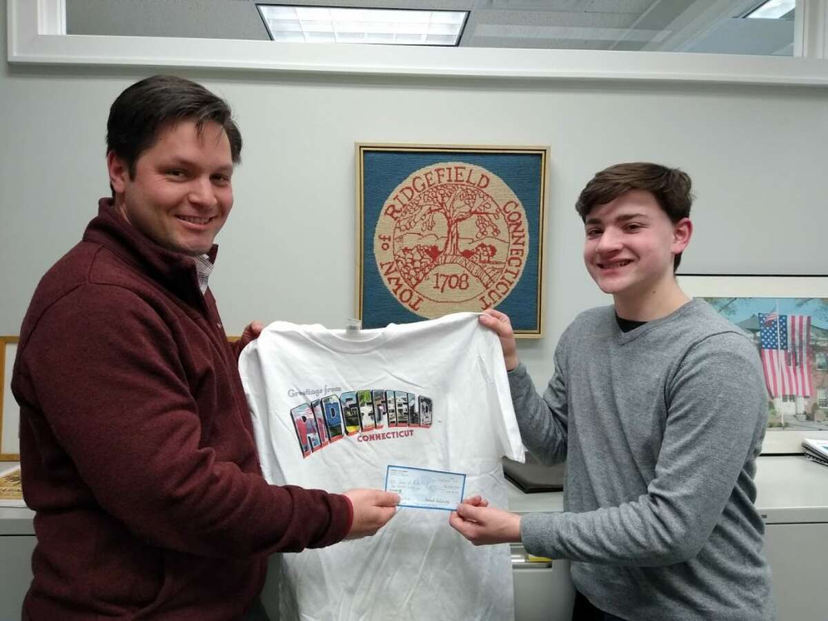 Tony Phillips, the town's director of Social Services, receives a donation check from Ridgefield High School junior Sam Sulzinsky.
