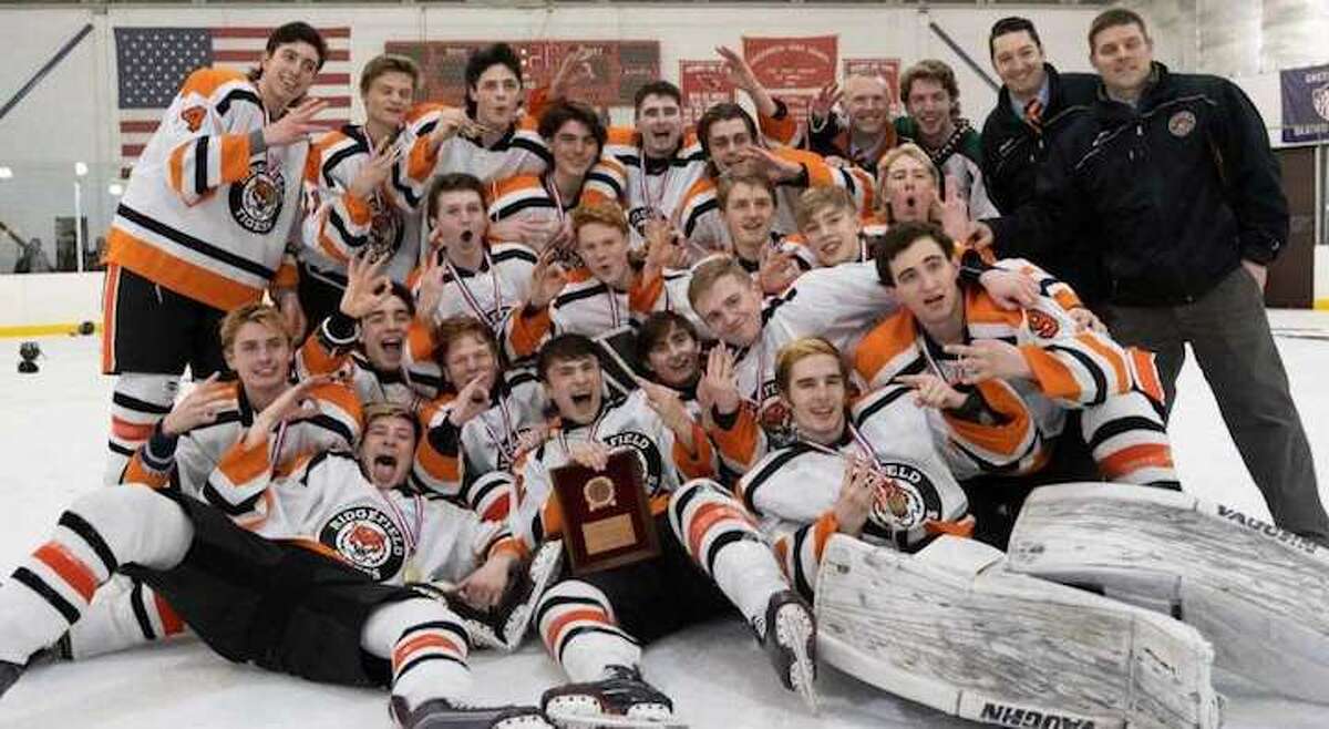 The Ridgefield High boys hockey team celebrates its third straight FCIAC title after beating Greenwich, 8-1, on Saturday. Photo: John McCreary / For Hearst Connecticut Media