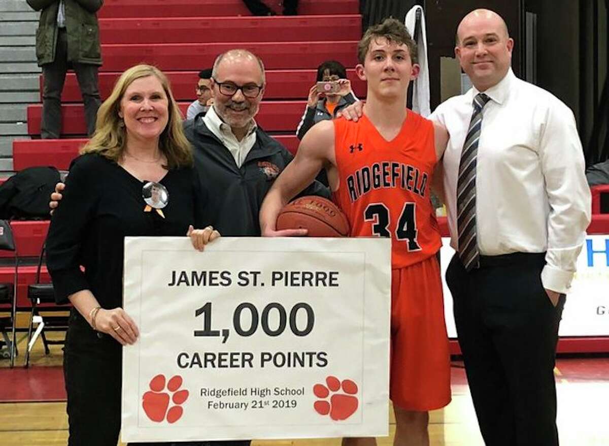 James St. Pierre was honored after scoring his 1,000th career point during Ridgefield's game at Fairfield Warde. St. Pierre is shown with his parents and Ridgefield head coach Andrew McClellan (far right). - Contributed photo
