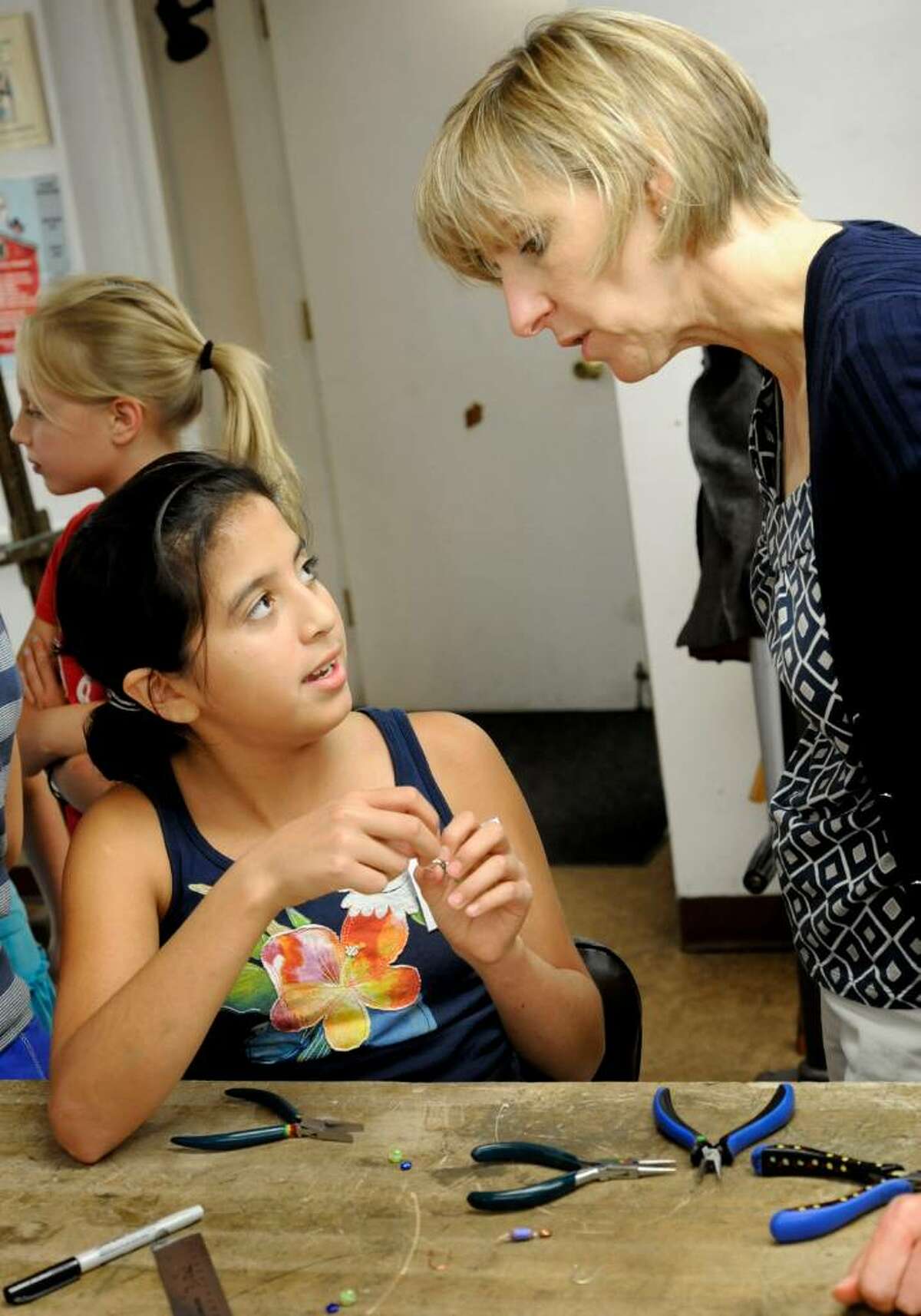 Volunteer Katee Sosa, 11,explains earring making to Barbara Stauder, 54, of Danbury, during the Brookfield Craft Center's Open House '09 on Sunday, Sept. 6, 2009.