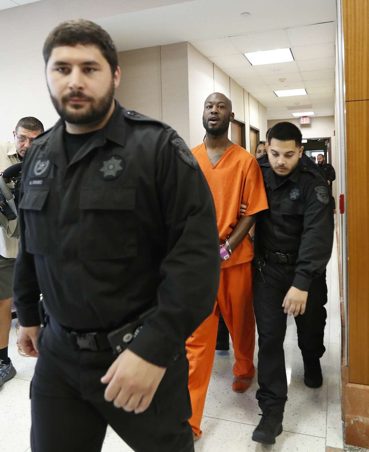 Houston police officers walk Andre Jackson - charged with the 2016 murder of 11-year-old Josue Flores, down the hallway of the Harris County Criminal Courts, Wednesday, June 19, 2019, in Houston. As he was being led to a back stairway, he said "I'm Grace Jones' son, fox."