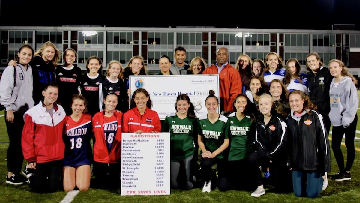 CHECKING IN — Darien's Emily DeNunzio (above FCIAC insignia on check), on behalf of the FCIAC girls' soccer teams, presents a check in the amount of $6,353 to the Lewis Family and Marlene Procino from Yale.