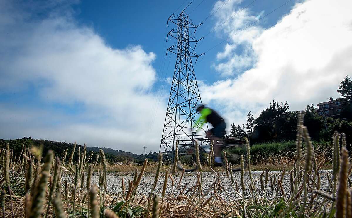 A bicyclist pedals by power lines in Mill Valley on Wednesday, June 19, 2019. PG&E is overhauling part of a major transmission line in Marin County that serves Sausalito.