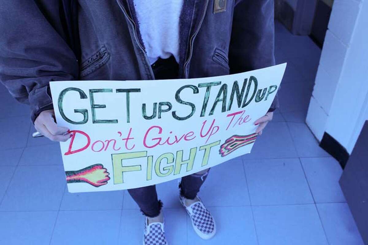 Maya Owainati is seen holding her sign which reads "GET up STAND up Don't Give Up The Fight".