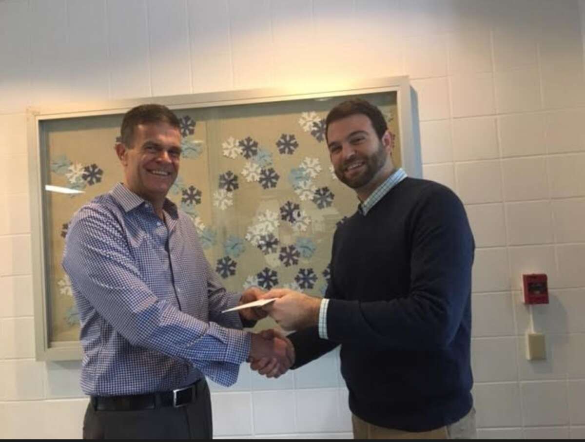 Geoff Garfield handed a check to Ox Ridge principal Dr. Luke Forshaw receiving check for the school's effort in helping sell tickets.