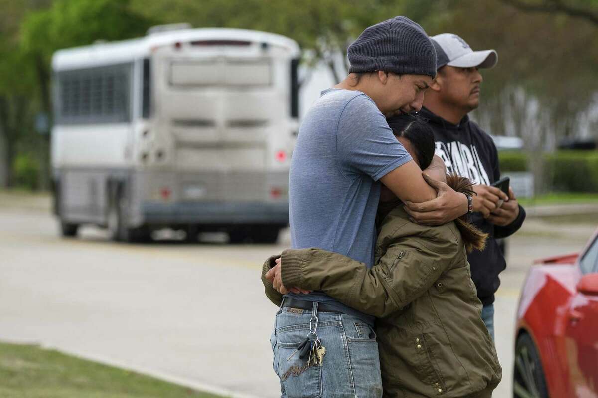 In this Wednesday, April 3, 2019 photo, a couple who did not want to give their names embrace outside CVE Group as a bus from LaSalle Corrections Transport departs the facility in Allen, Texas. U.S. Immigration and Customs Enforcement officials were detaining people at an Allen technology business Wednesday. The operation began Wednesday morning at CVE Group, a New Jersey-based company that refurbishes cellphones and other technology, on Enterprise Drive near East Bethany Drive and U.S. Highway 75. (Smiley N. Pool/The Dallas Morning News via AP)