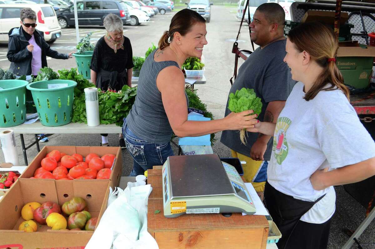 Karen Panza, of Stratford, buys vegetables from Rose Gazy, of Gazy Farms in Oxford during the opening day of the Walnut Beach Farmers' Market at the Walnut Beach pavilion in Milford, Conn., on Thursday June 20, 2019. The market will be held every Thursday until Sept. 12 from 4-7 p.m.