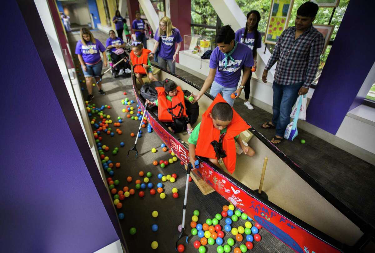 Neveah, from left, 4, Eshal, 5, and Jaiden, 7, pick up colorful balls from a canoe simulating a fishing trip from a hallway of the Texas Children’s Hospital as part of a summer camp experience in the hospital on Tuesday, June 11, 2019, in Houston.