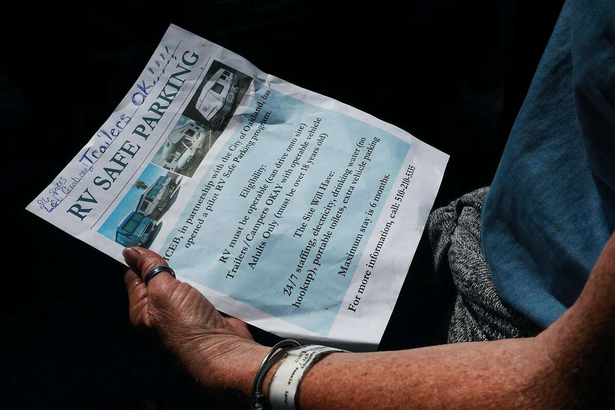 Eileen Mulcahy, 57, holds a flyer advertising a pilot RV Safe Parking Parking program, located at 771 71st. Ave., as she stands in front of her neighbor's RV near 85th Ave. and Baldwin St. in Oakland, Calif., on Thursday, June 20, 2019. "There are so many abandoned buildings and abandoned warehouses that could be like given to us ... to get us off the streets and maybe to empower us, to be able to say, 'Okay, this could be ours.'" Mulcahy said. "Millions of dollars was allocated for the homeless. A little bit went to the tuff sheds, that's like concentration camps to me because you're being watched."
