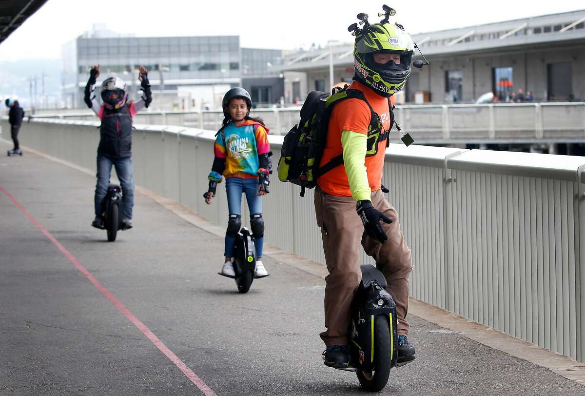 Jesse Garnier (right) departs Pier 15 with his wife Miles and their niece Alexis Villanueva, 11, aboard electric unicycles for a weekly 23-mile group ride by Bay Area Esk8 in San Francisco, Calif. on Saturday, June 15, 2019. Electric unicycles have become a popular mode of transportation.