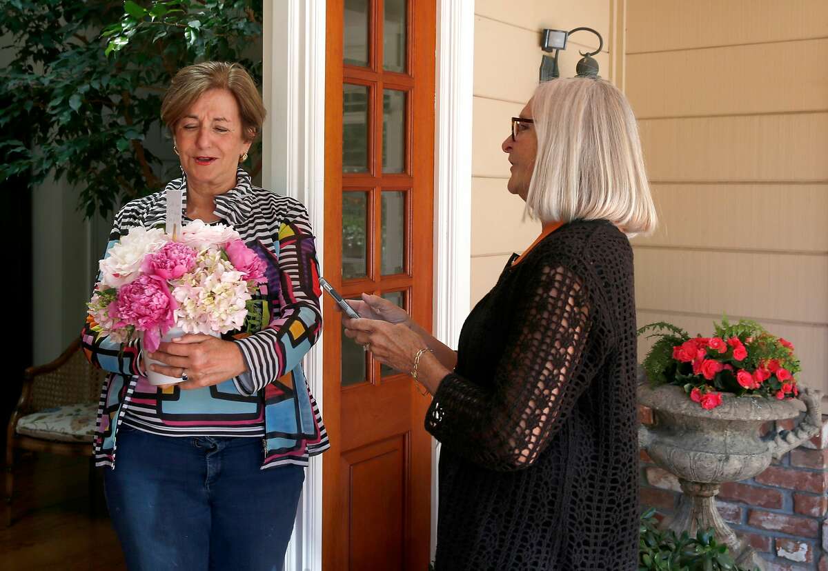 Lynne Richardson (right), a driver for deliv.co, delivers a flower arrangement to Cachi Kenna in Atherton, Calif. on Friday, June 21, 2019.