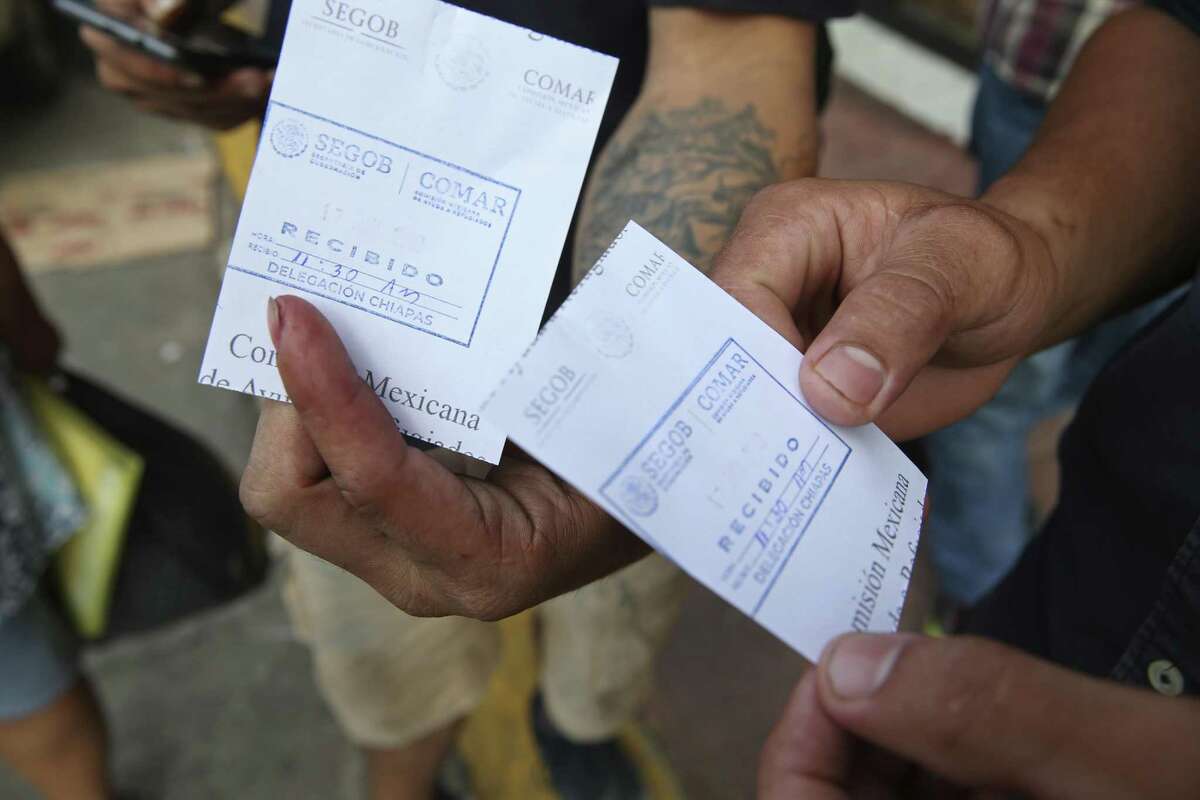 Migrants show their appointment details in front of the Mexican Commission of Assistance to Refugees, (COMAR), in Tapachula, Mexico, Monday, June 17, 2019. Hundreds of mostly Central American migrants line up early in hopes of securing an appointment to plea their case for a humanitarian visa.