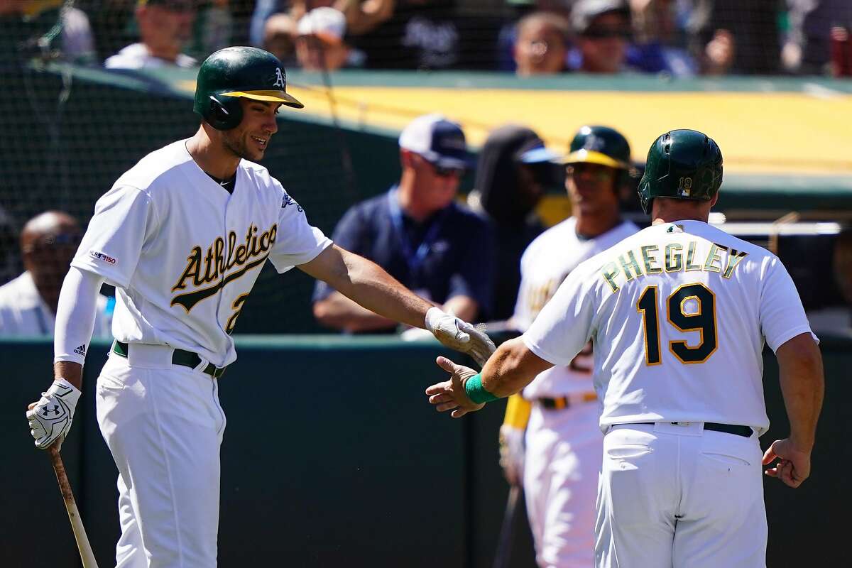OAKLAND, CA - JUNE 22: Josh Phegley #19 celebrates scoring with Matt Olson #28 of the Oakland Athletics during the seventh inning against the Tampa Bay Rays at Oakland-Alameda County Coliseum on June 22, 2019 in Oakland, California. (Photo by Daniel Shirey/Getty Images)