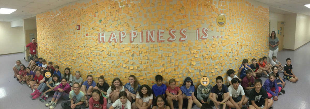 New Canaan Public Schools recently presented their health curriculum update to the Board of Education. This “Happiness Is” wall outside a classroom at Saxe Middle School is where students place affirmations on sticky notes to promote a constructive mindset. — Contributed photo