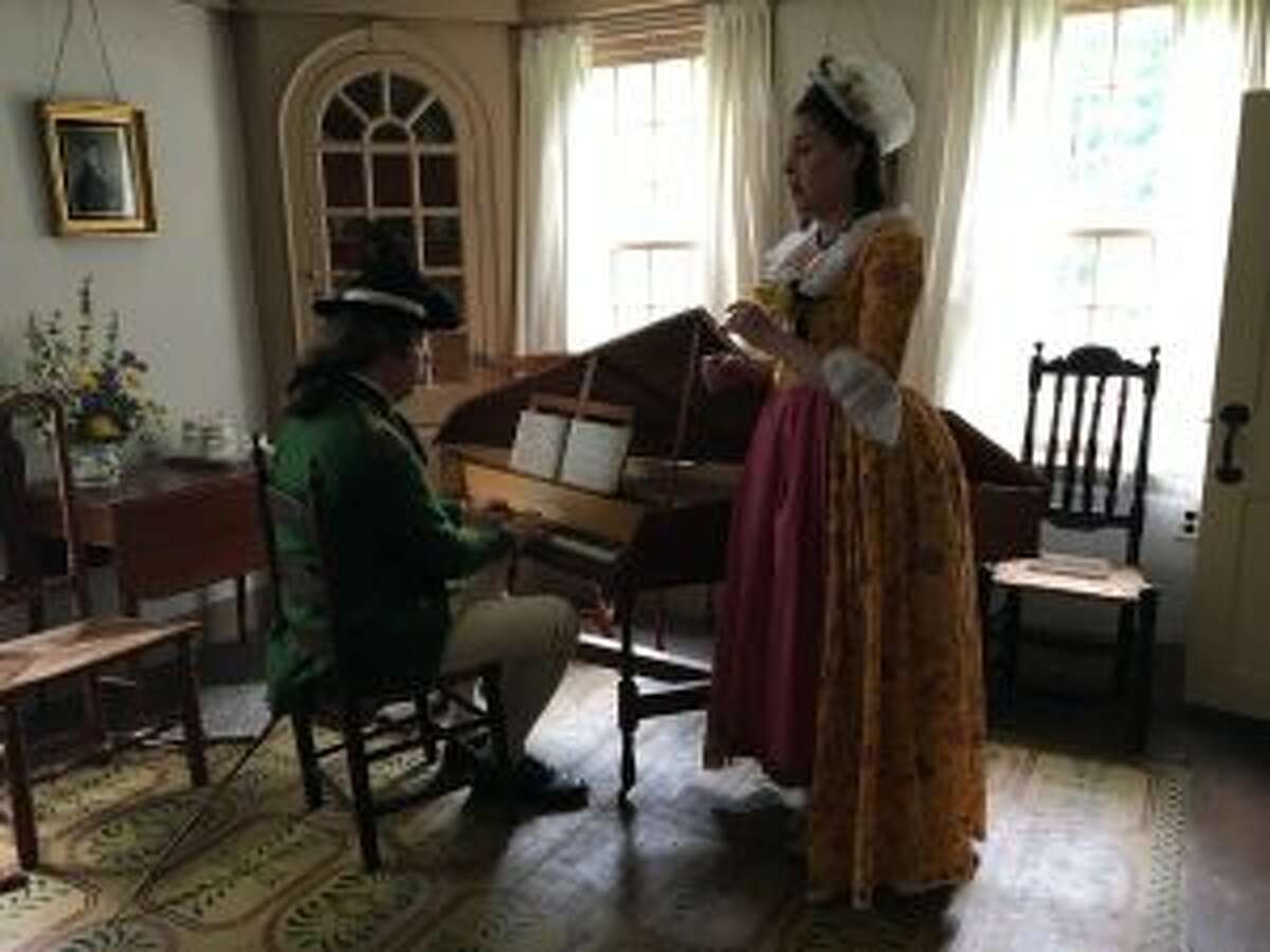 Two reenactors, in costume, perform a song on a harpsichord. — Luca Triant photo