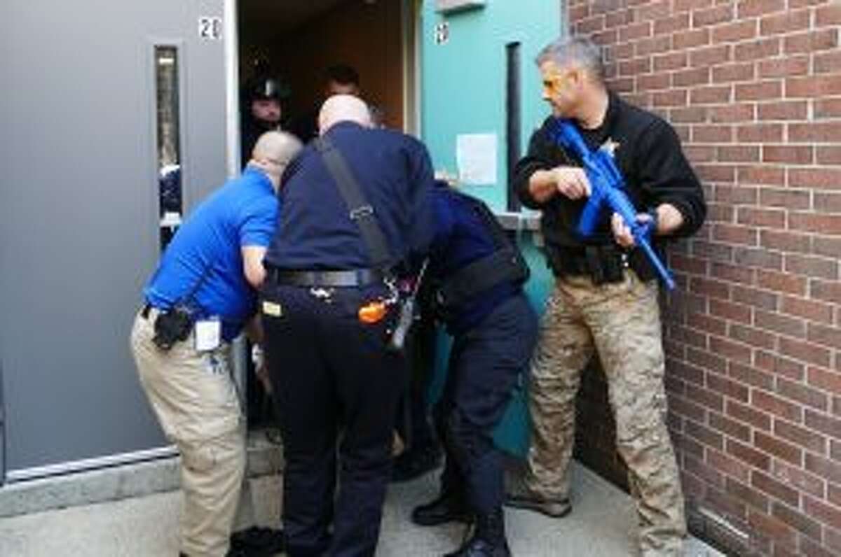 During a New Canaan emergency training exercise, Patrol Officer and Saxe Middle School Resource Officer, Jeff Deak, is standing with a rifle by the back door of East School. The drill is part of a program called the Medical Preparedness and Response to Dynamic Incidents (MPaRDI).  — Grace Duffield photo