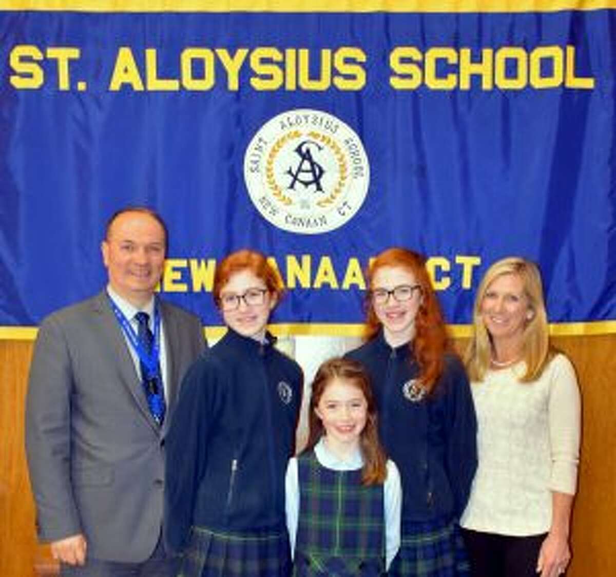 New Canaan: St. Aloysius's 'Read to Feed' in Lent shined light on the Heifer Project. Principal Bardhyl Gjoka and Read To Feed Coordinator Deborah Moran, reward winners in the student contest Anna Gayer, left; Noelle Gayer, right; and Lilly Gayer, front. — Contributed photo