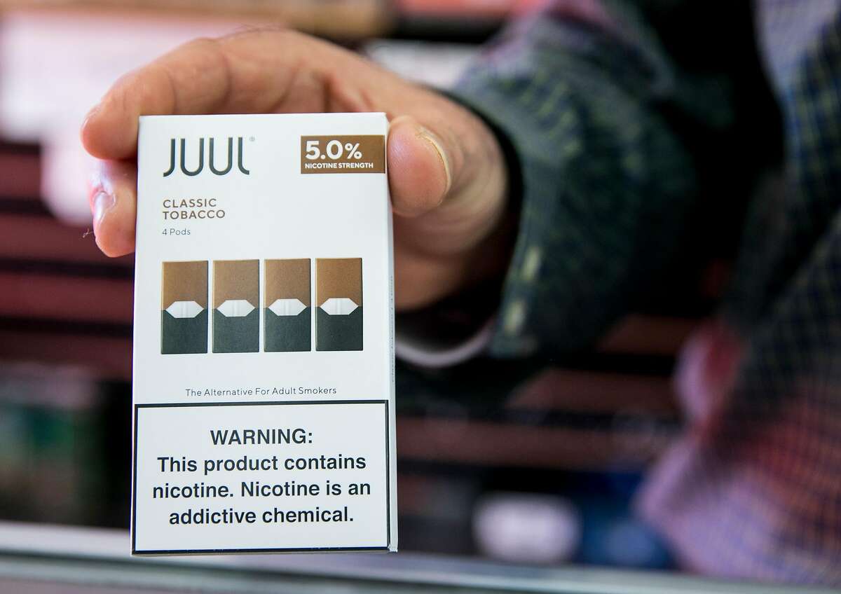 Walid Rahman holds a Juul cartridge container while working behind the counter at The Town Smoke Shop in the Mission district of San Francisco, Calif. Thursday, March 21, 2019.