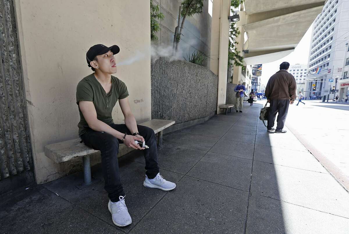 In this Monday, June 17, 2019, photo, Jacky Chan, 23, takes a vaping break from his job at a smoke shop in San Francisco. San Francisco supervisors are considering whether to move the city toward becoming the first in the United States to ban all sales of electronic cigarettes in an effort to crack down on youth vaping. The plan would ban the sale and distribution of e-cigarettes, as well as prohibit e-cigarette manufacturing on city property. (AP Photo/Samantha Maldonado)