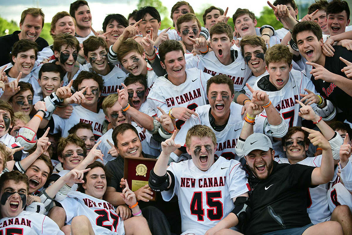 The New Canaan Rams celebrate with their head coach Chip Buzzeo after beating Wilton in the FCIAC boys lacrosse final Friday night at Brien McMahon High School. — Erik Trautmann/Hearst Connecticut Media