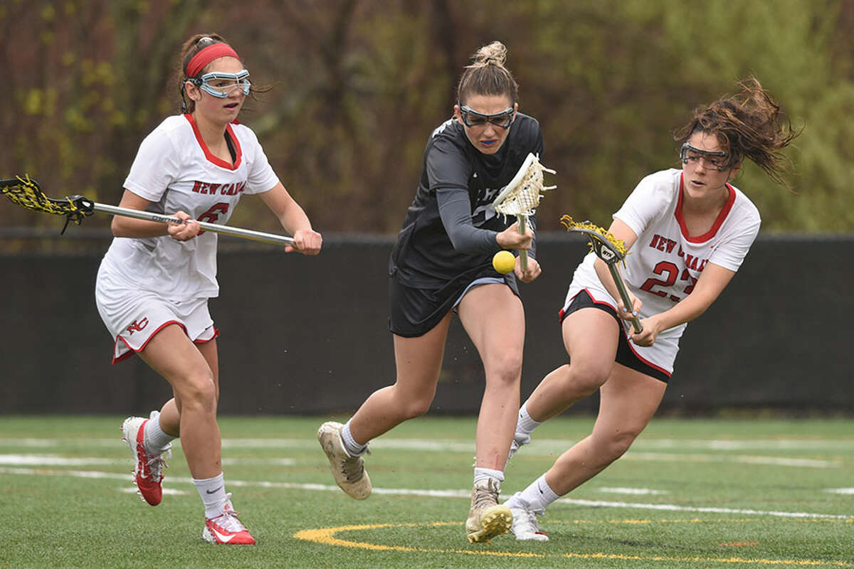 New Canaan’s Natalie Lopez (23) knocks the ball away from Henna Brennan (2) of Longmeadow, Mass., as New Canaan’s Kaleigh Harden (6) also defends during Saturday's girls lacrosse game at Dunning Field. — Dave Stewart/Hearst Connecticut Media
