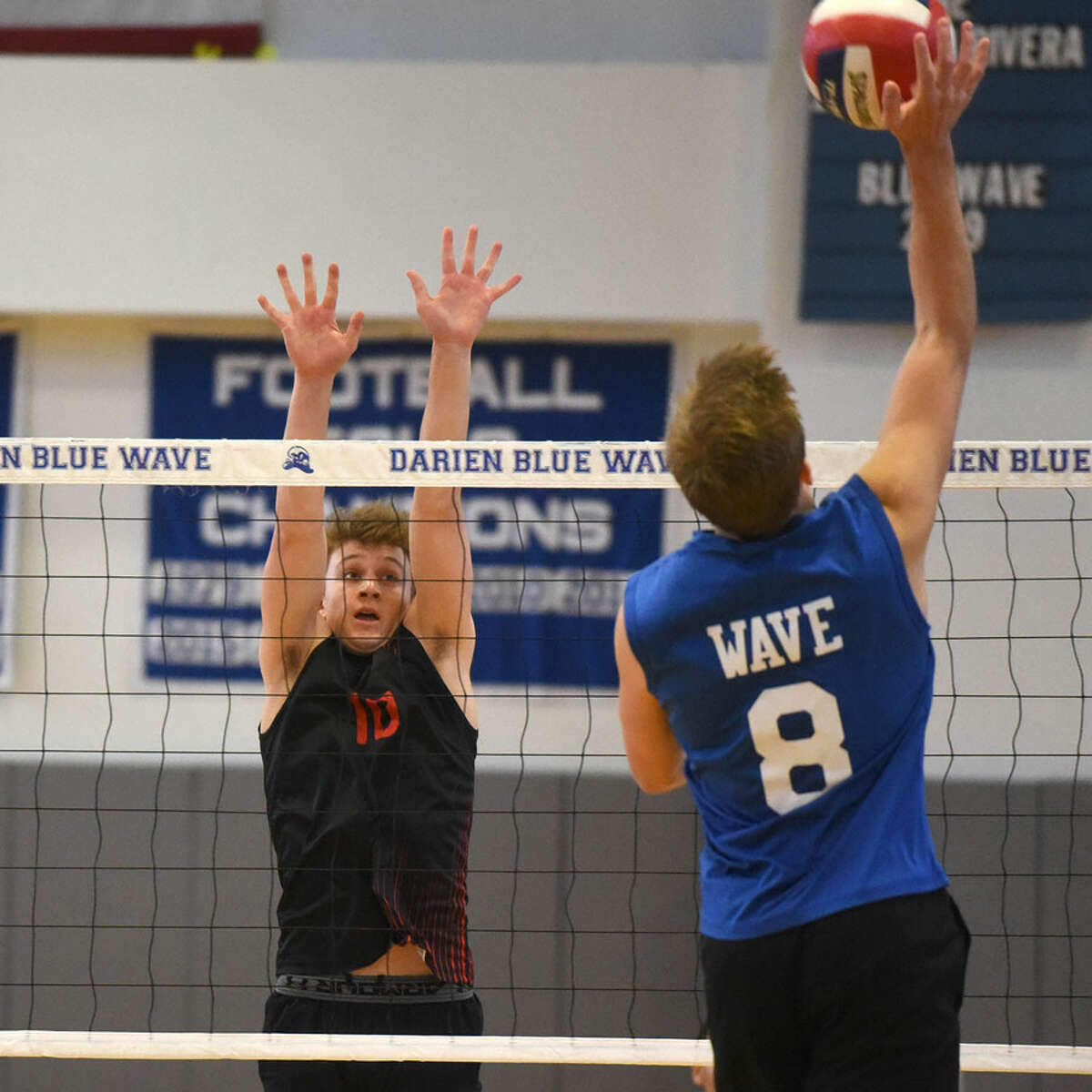 New Canaan’s Gavin Bramwit (10) goes up to defend as Darien’s Tyler Herget (8) hits a shot during a boys volleyball match on Wednesday. — Dave Stewart/Hearst Connecticut Media