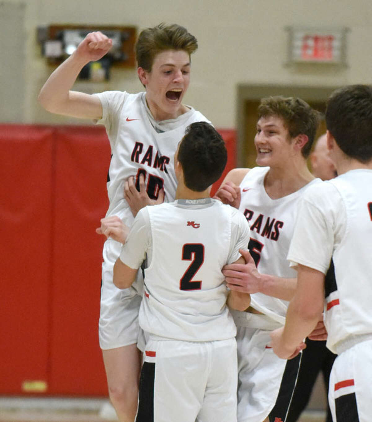 Ryan McAleer (10) and Alex Gibbens celebrate with Aaron Fishman (2) after Fishman hit three free throws to tie the score with 0.9 seconds remaining. — Dave Stewart/Hearst Connecticut Media