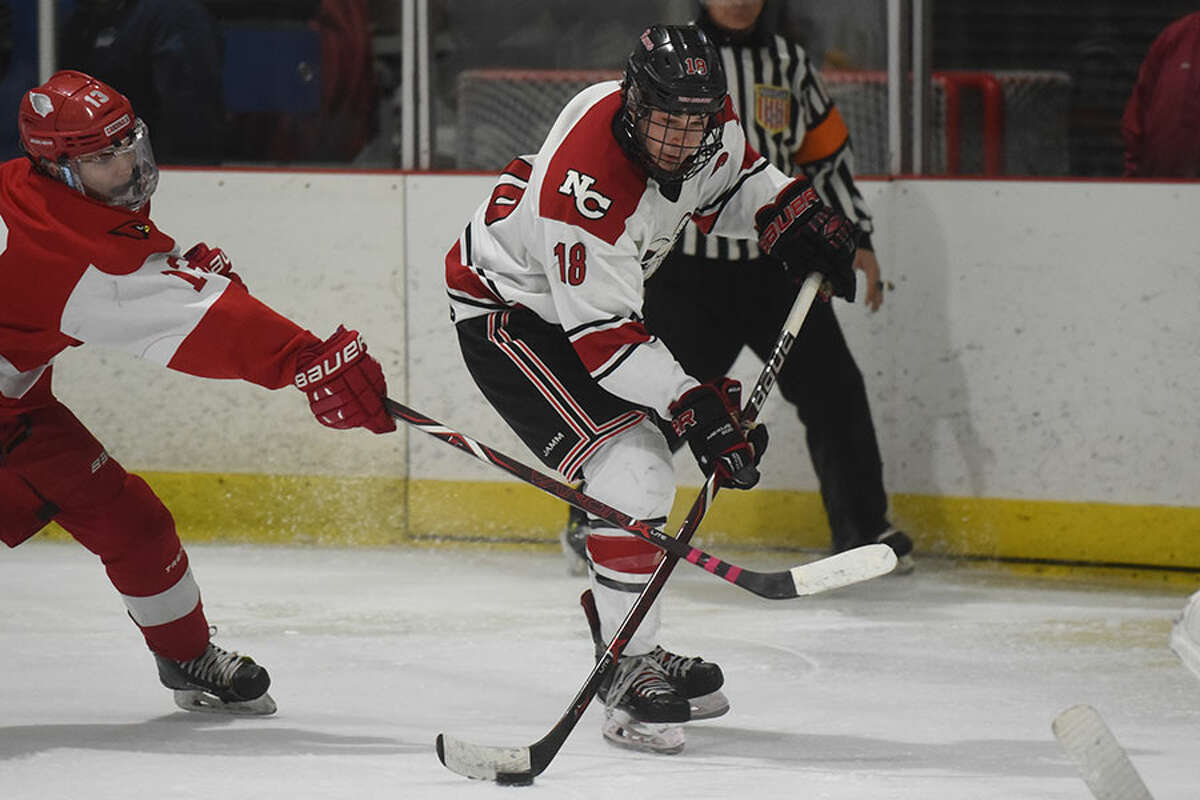 New Canaan's Gunnar Granito (18) drives to the net as Greenwich's Ryan Columbo (13) during the FCIAC playdowns at the Darien Ice House on Saturday, Feb. 23. — Dave Stewart/Hearst Connecticut Media photo