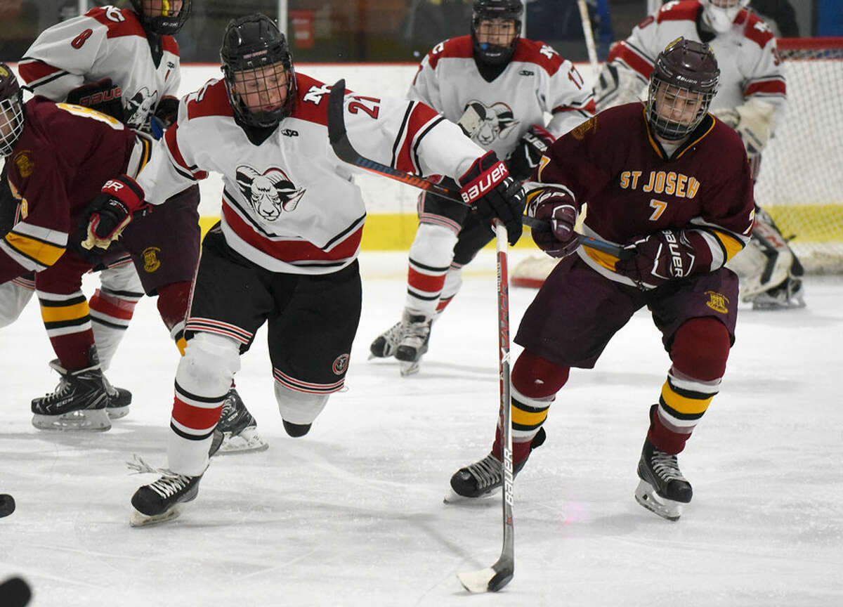 New Canaan’s Carter Ellis (21) and St. Joseph’s Kyle Marcinko (7) pursue the puck during a boys ice hockey game at the Darien Ice House on Monday, Jan. 7. — Dave Stewart/Hearst Connecticut Media photo