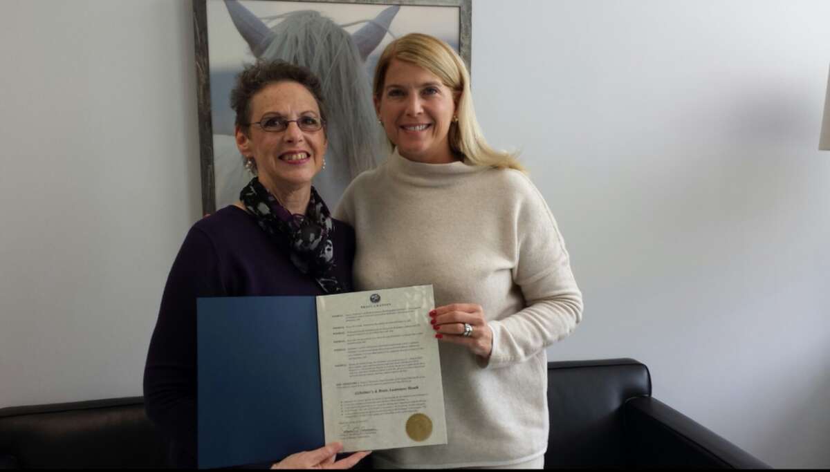 Robin Roscillo, a volunteer for the Alzheimer's Association, left, picking up the Proclamation at Town Hall from First Selectman Jayme Stevenson.