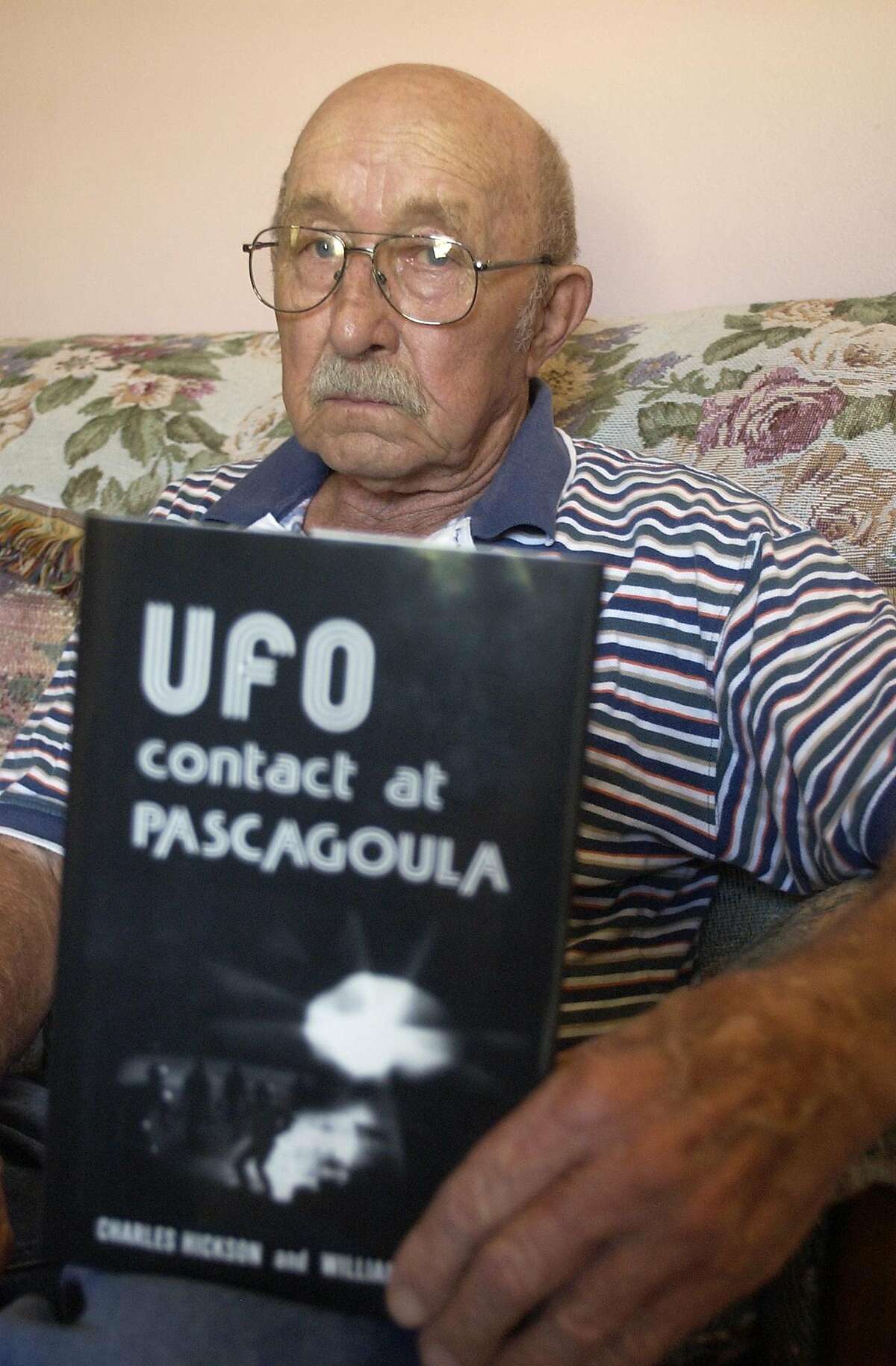 Charles Hickson poses with his book "UFO Contact at Pascagoula," Oct. 3, 2003, in Pascagoula, Miss. For 30 years, Hickson has told the story of how he was catapulted into celebrity when, according to him, 5-foot tall, flesh-colored aliens floated him off a Pascagoula pier onto their space ship for a head-to-toe probe. (AP Photo/The Mississippi Press, Carisa McCain)