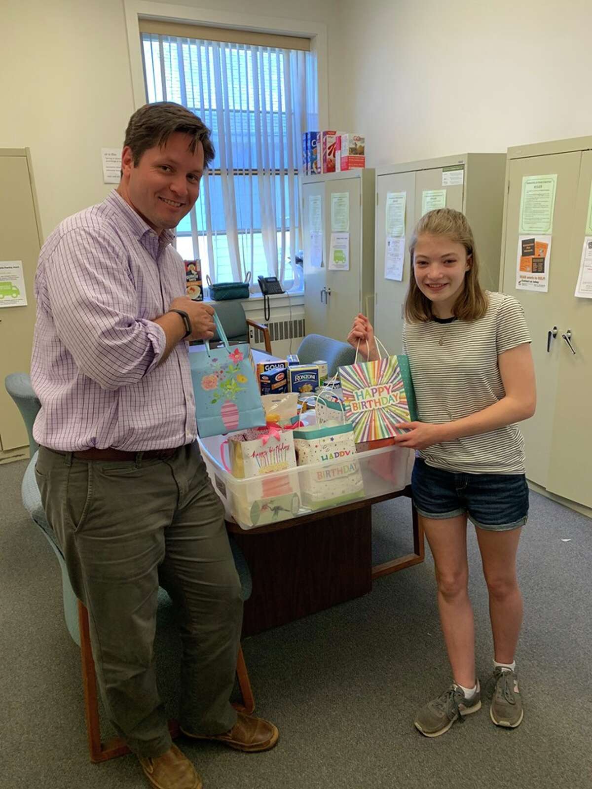 Devon Noonan, who graduated from East Ridge Middle School in June, stands with Social Services Director Tony Phillips inside the food pantry at town hall. Before her graduation, Devon dropped off a whole bin of “Birthday Bags.” She and other students and teachers collected birthday bag items for food pantry consumers.