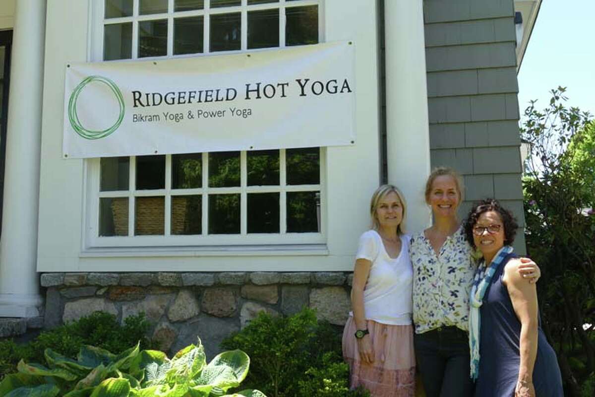 The Ridgefield Hot Yoga team, from left: Wendy Boscia, Leah Bey-Wagner and Maritza Johnson in front of the studio's new sign.
