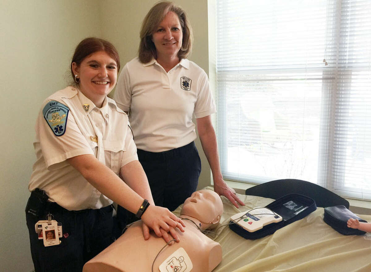 Wilton EMTs Elana Everett and Libby Nagle demonstrate Hands-Only CPR at Wilton Commons. - Patricia Gay Hearst Connecticut Media photo